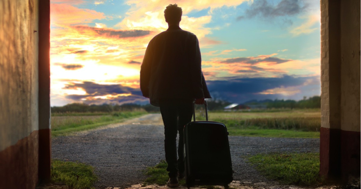 a man walking away with a suitcase, how being a guest liberates us