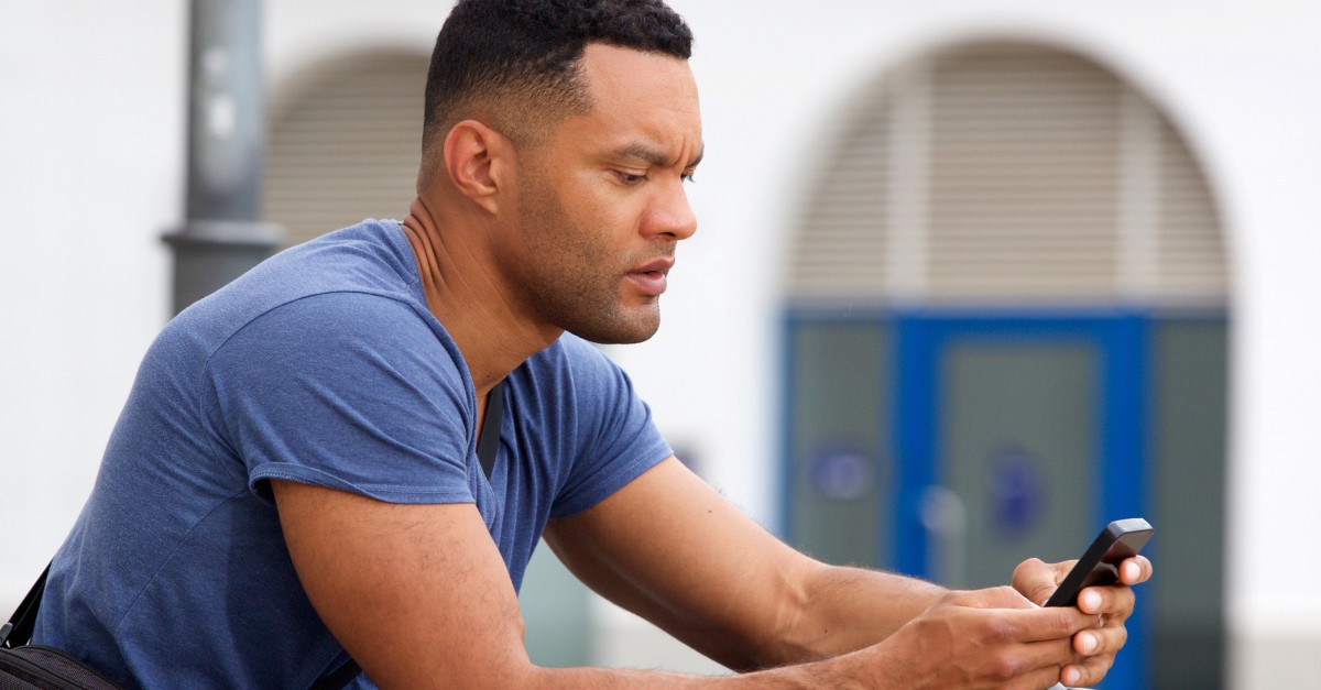 man staring seriously at cell phone