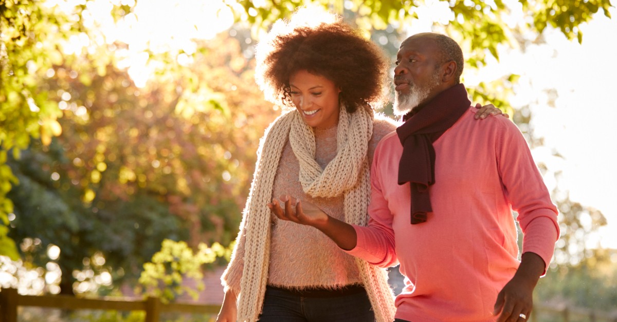 senior dad walking in park with adult daughter