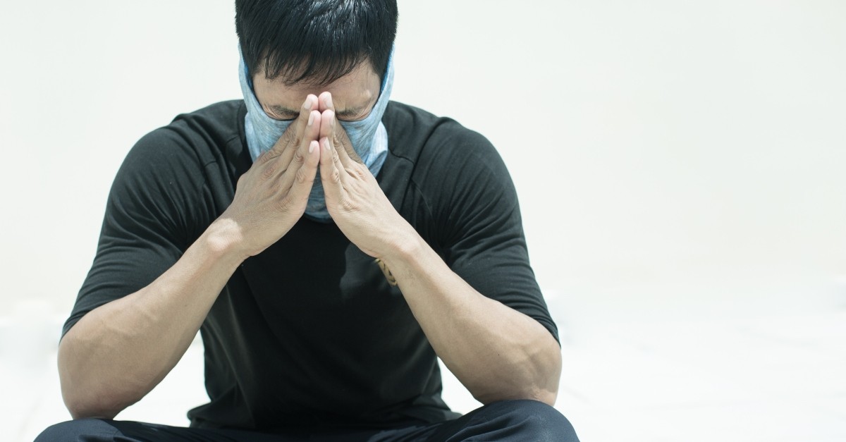man praying for healing from coronavirus with face mask on