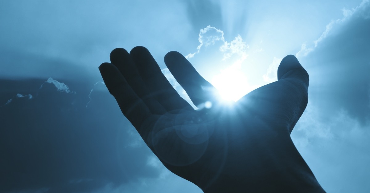 hand open up to sunburst through cloud in praise to God