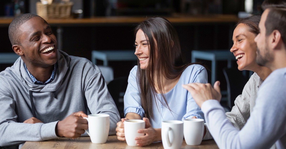 Happy friends smiling and laughing over coffee; 