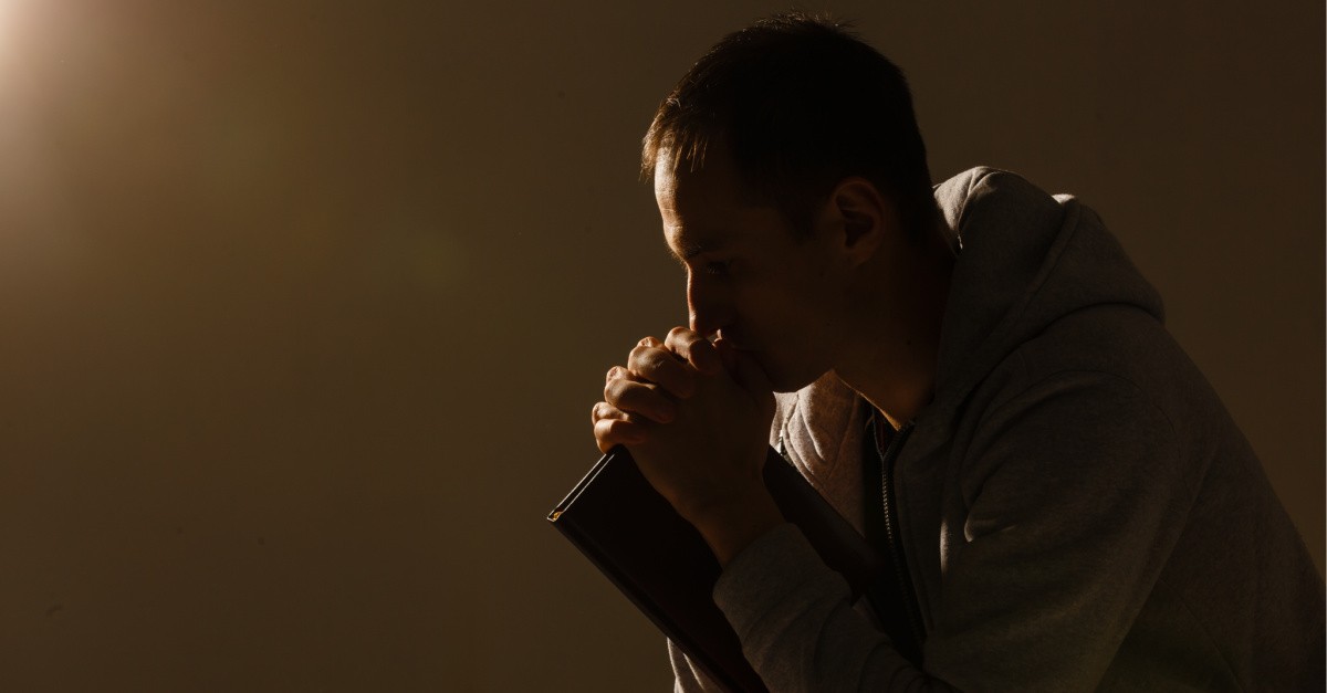 A man praying and holding a Bible,