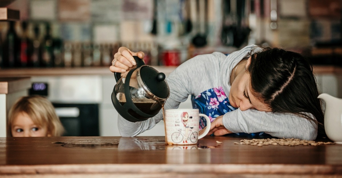 Tired mom pouring coffee on the table, instead of her mug