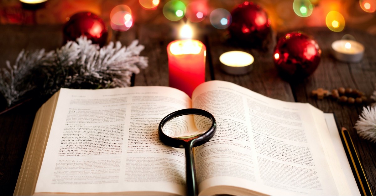 Bible opened in front of a Christmas tree with a magnifying glass on top