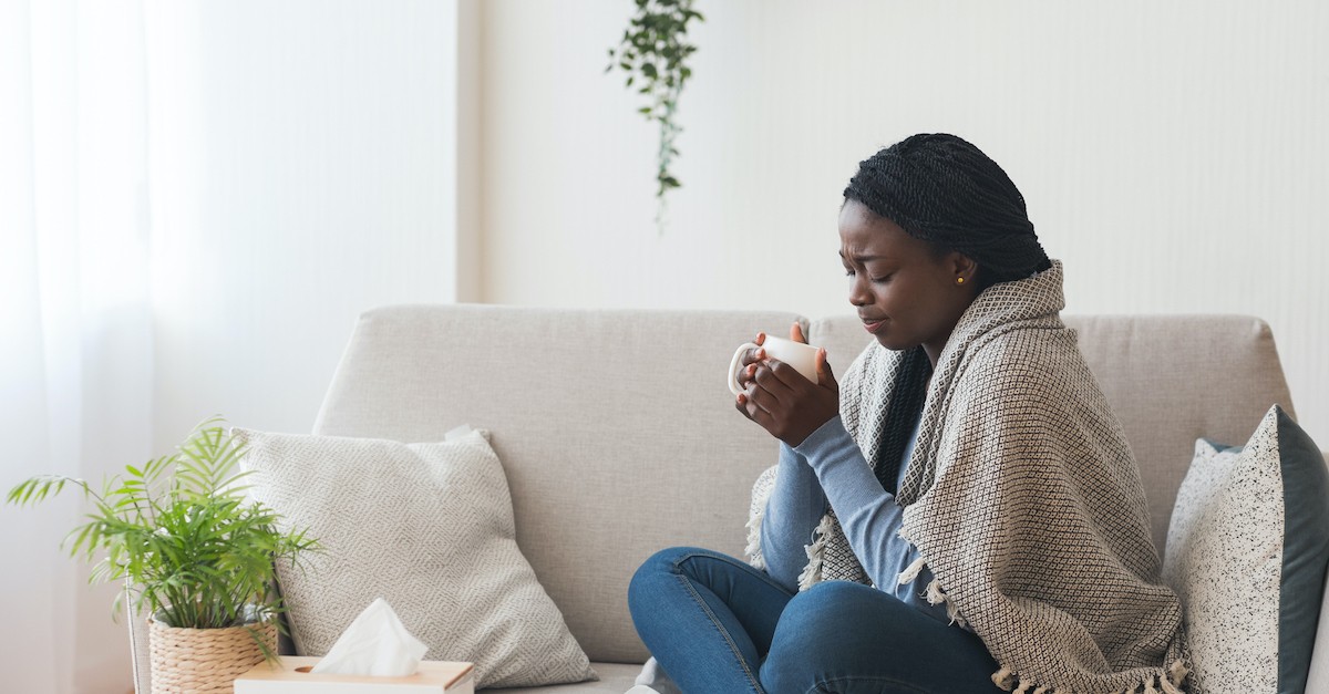 woman sitting on couch holding coffee mug with blanket thinking, the spirit is willing but the flesh is weak