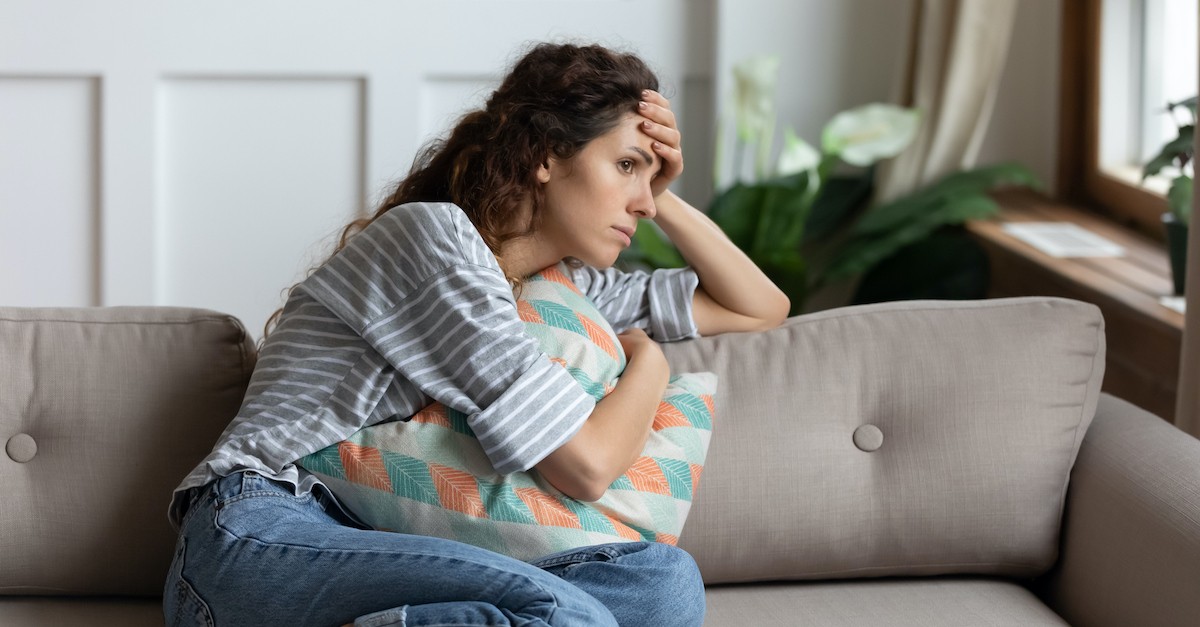 woman sitting on couch looking worried or unsure, does God hate me when I sin?