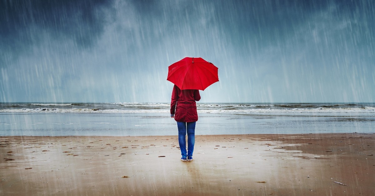woman standing with umbrella in rain on beach, myths in church about mental health