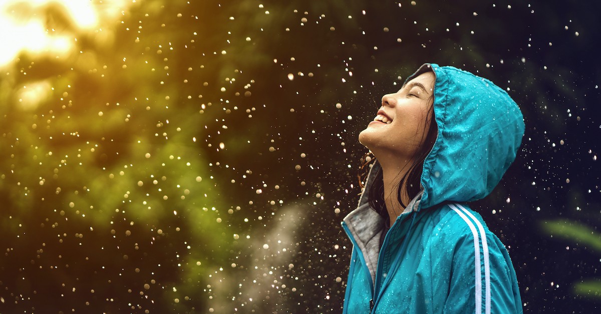 happy woman smiling in the rain with sunshine peaking through clouds, what is joy