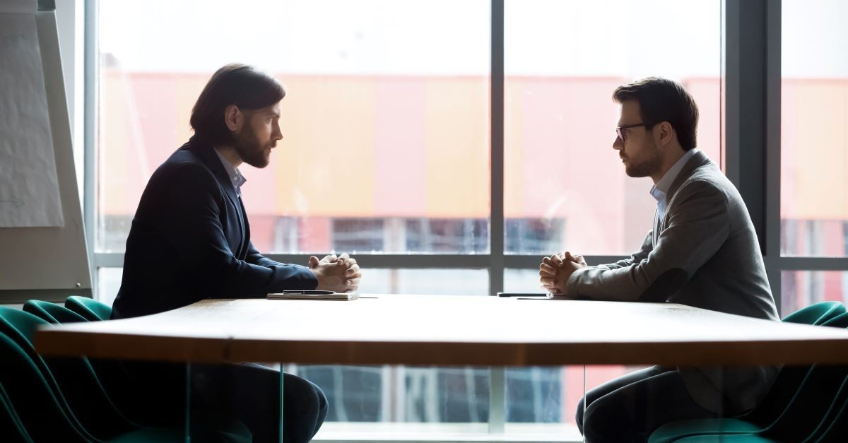 two men across table enemies upset fighting enemy