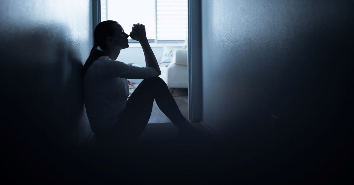 woman sitting on floor dark room praying hopeless