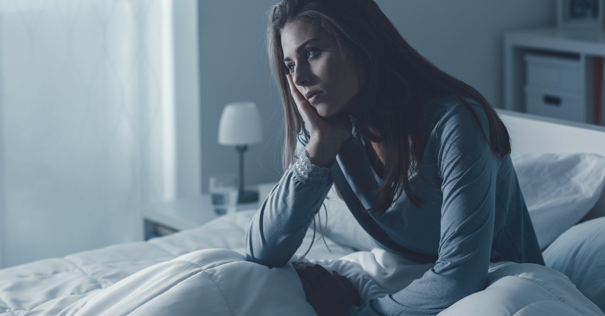 woman sitting up in bed looking anxious can't sleep, psalms for when you can't sleep
