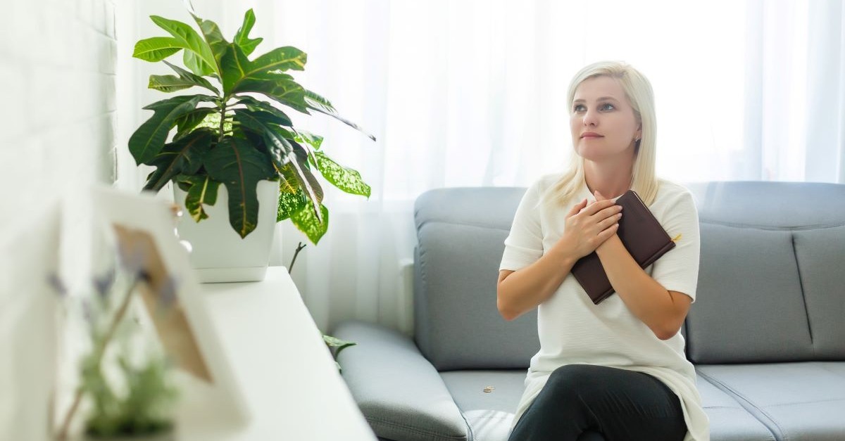 woman holding bible praying looking up praying clutching