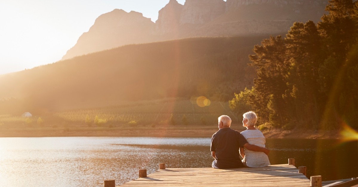 Senior couple sitting on a dock at sunset