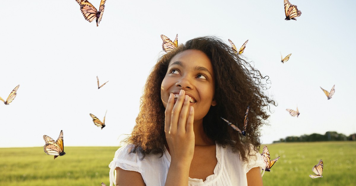 happy woman standing outside surrounded by butterflies, overcome evil with good