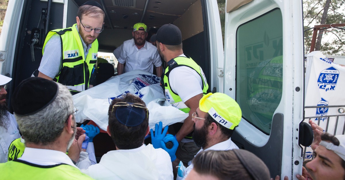 Men placing a dead body in an ambulance, At least 45 are killed in a religious celebration turned stampede