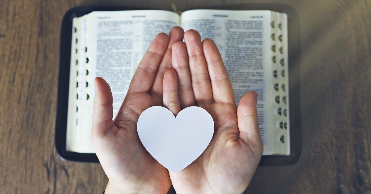 Hand and heart over the Bible