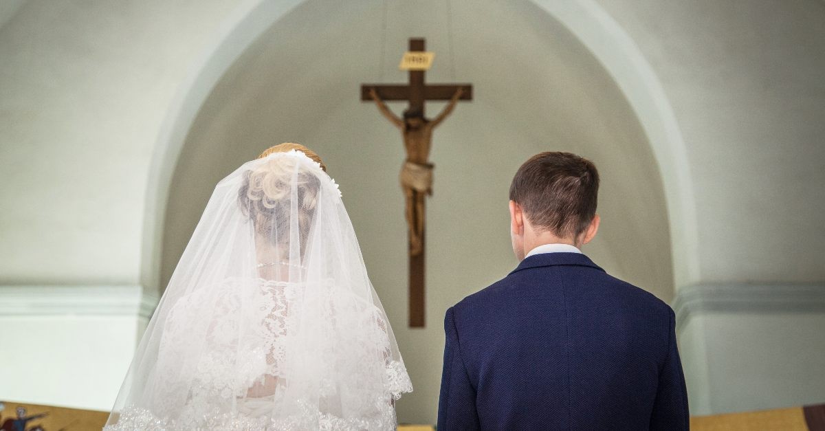 Bride and groom kneeling before the cross