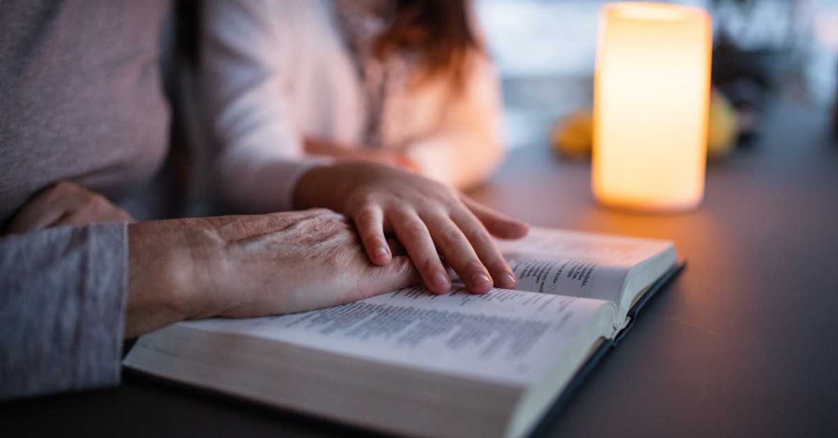 A small girl and grandmother reading Bible at home