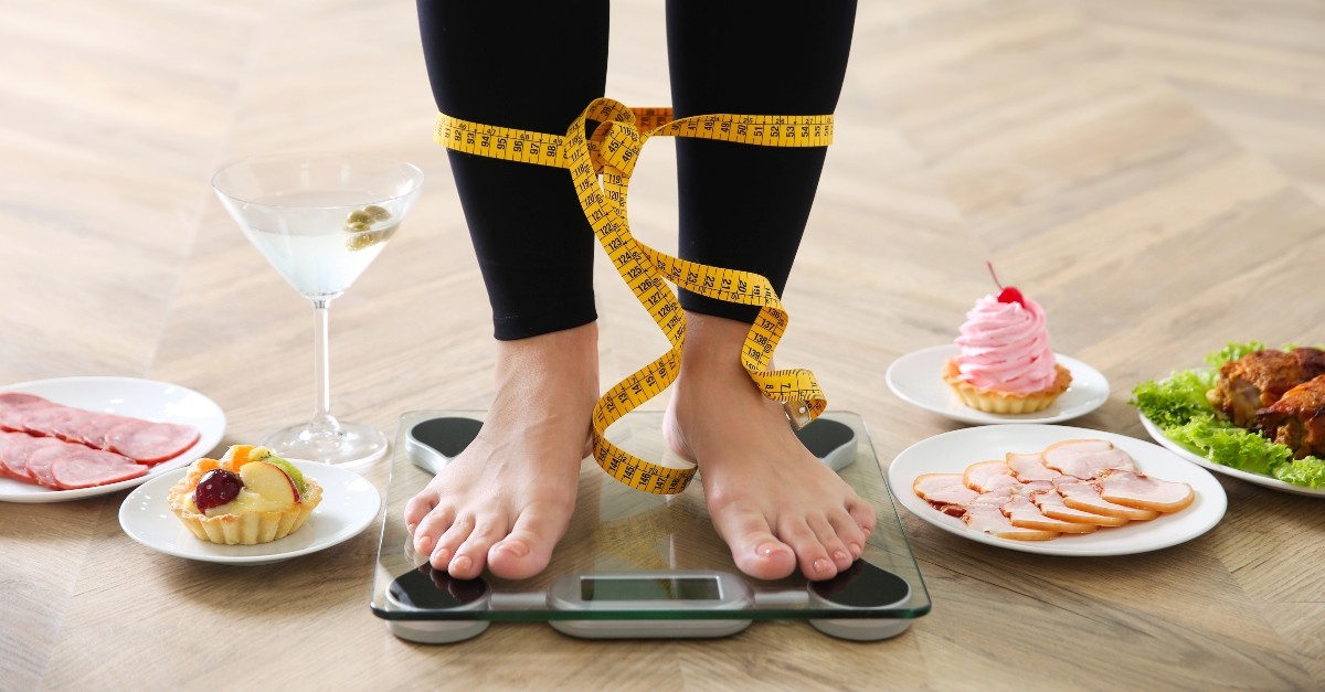 Woman on a scale with junk foods around her