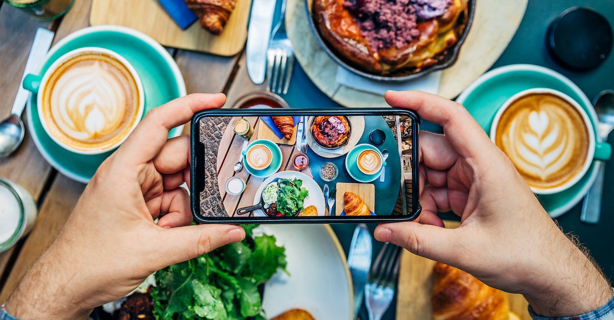 person taking a picture of their food on a table at a restaurant