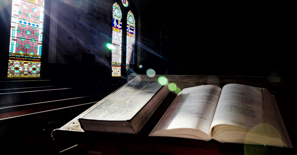 Bible siting on church pulpit with light streaming through stained glass window