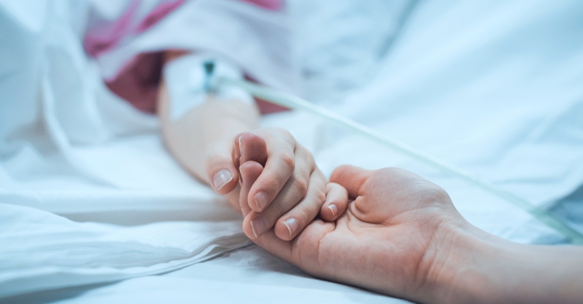 Woman holding a sick person's hand in the hospital