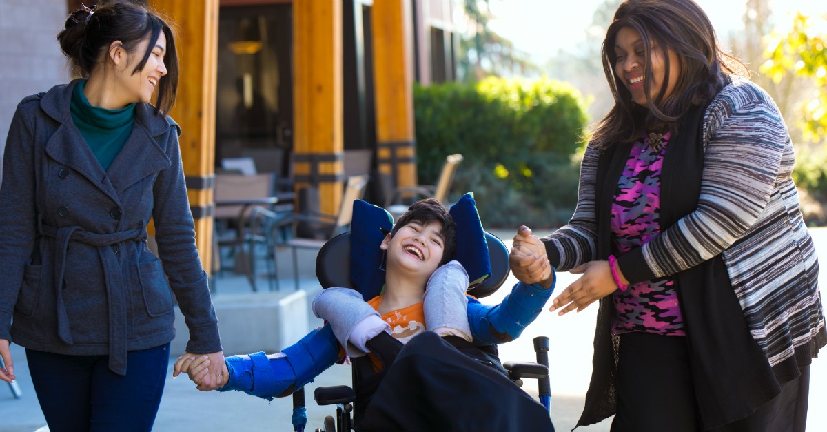 two women friends helping boy in wheelchair