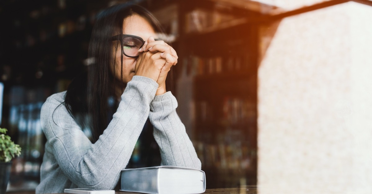 woman praying in front of window