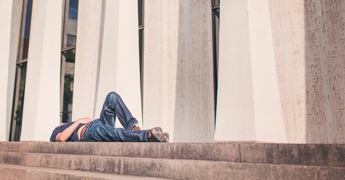 lazy man lying on the sidewalk