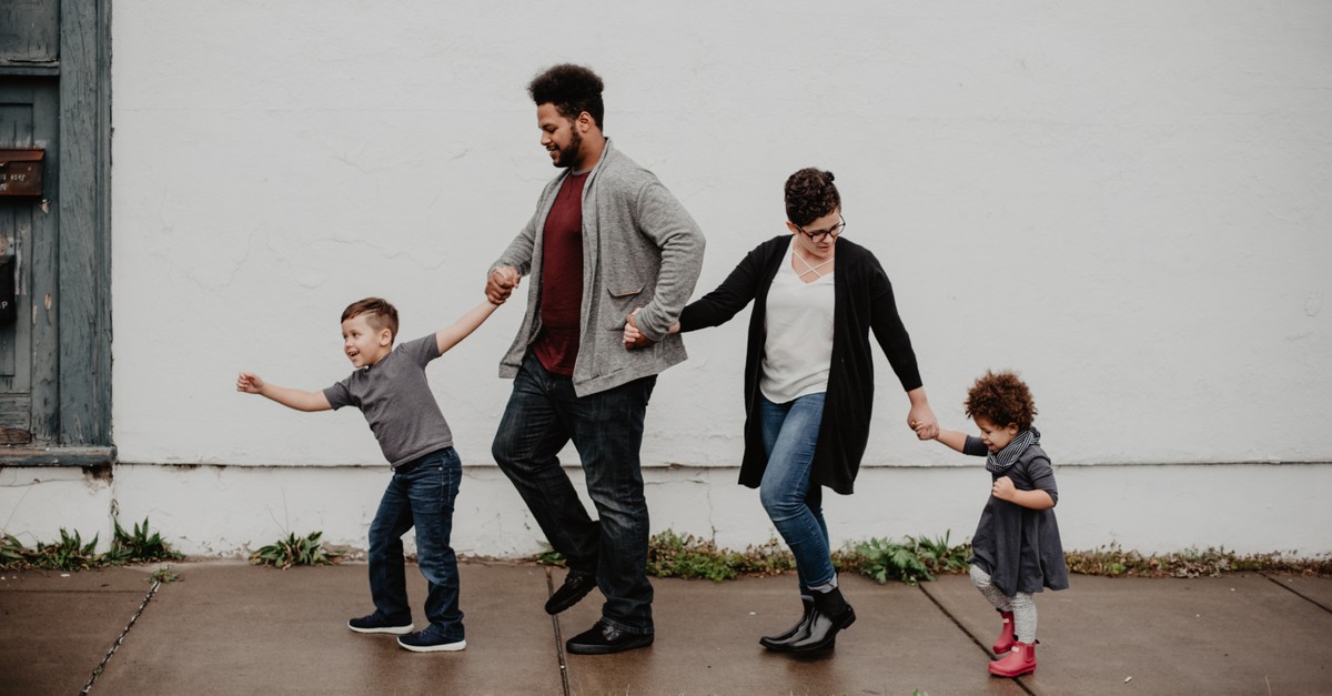 family walking together on sidewalk holding hands