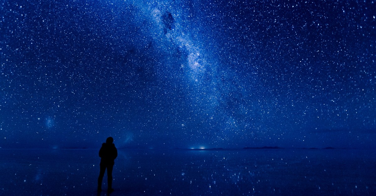 silhouette of person looking up at blue starry sky in nature, God is wise