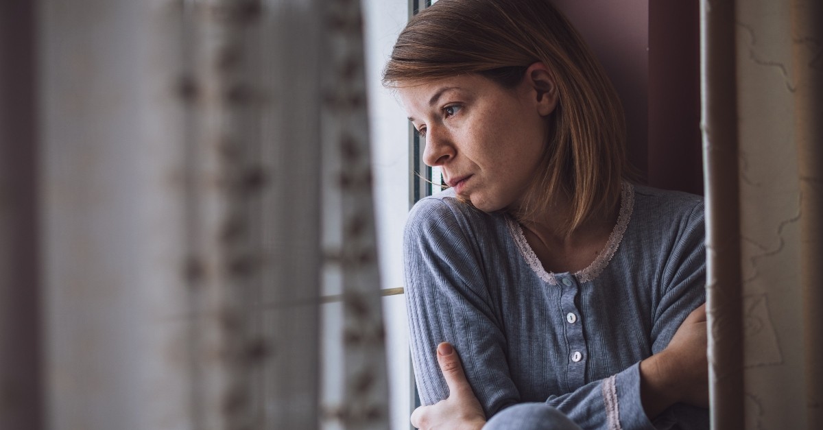 sad woman looking out apartment window