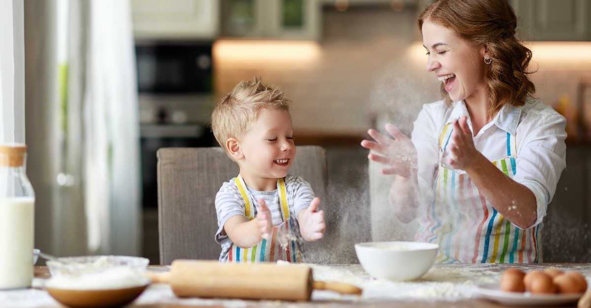 Mother and son laughing while cooking in the kitchen; what are the most popular mother-son wedding songs?