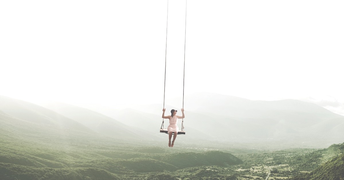 Woman hanging on swing over a valley