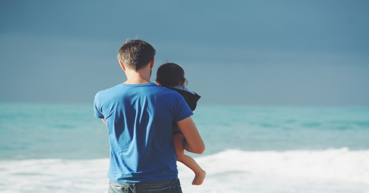 father at beach holding child