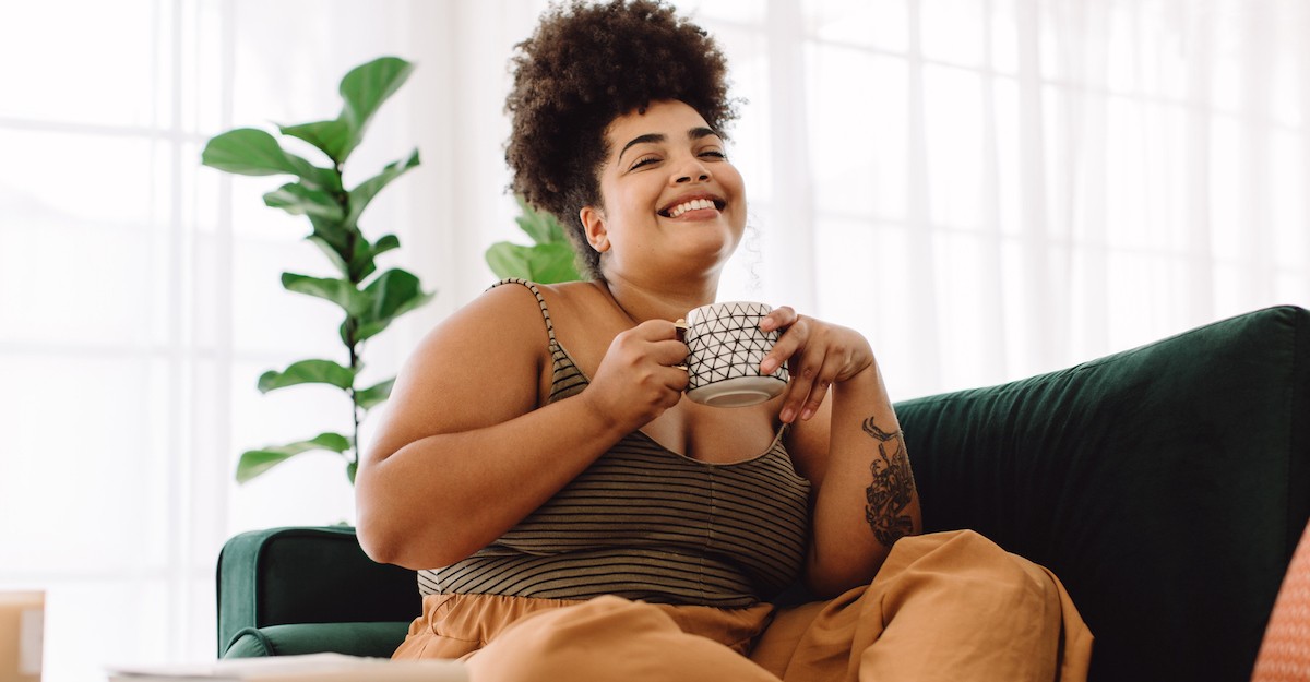Happy single woman in home sipping coffee