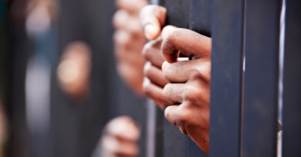 Hands reaching through prison bars, persecuted church