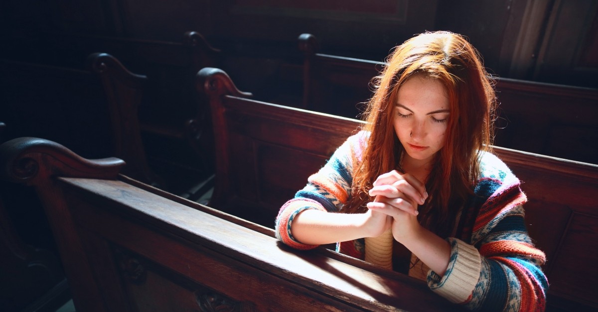 Woman praying in a church pew