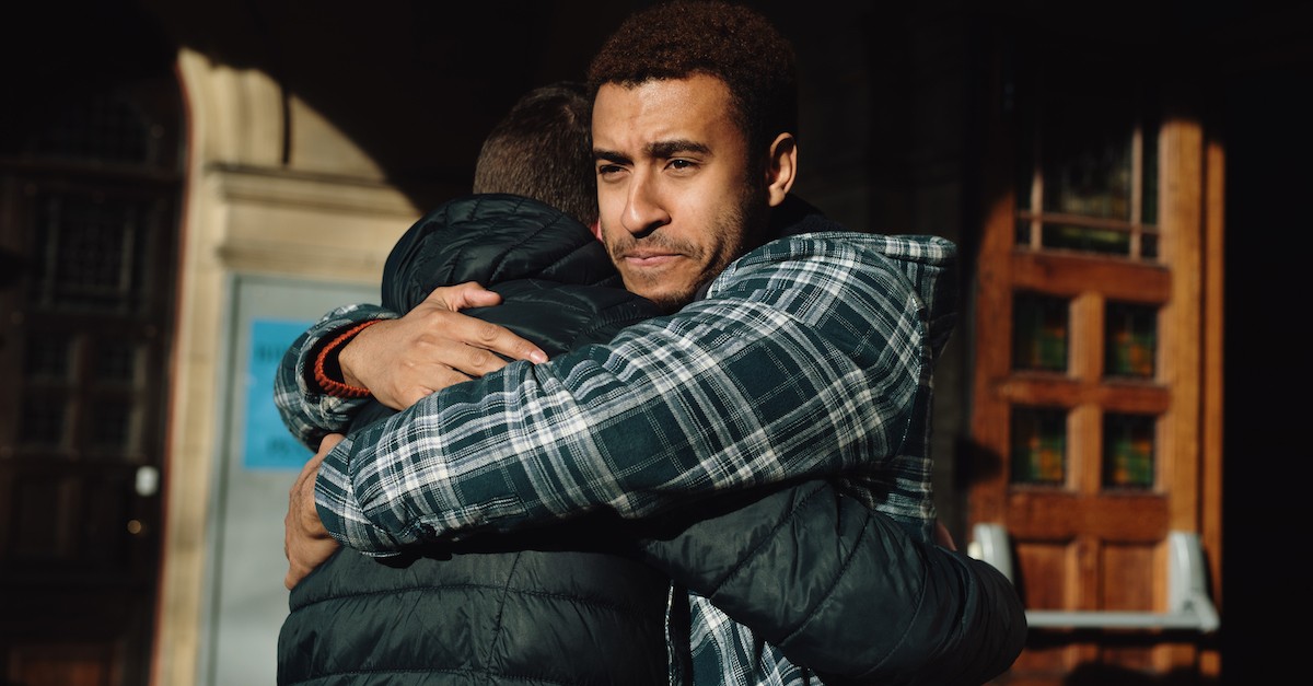 sad man hugging another man as friends; how can I help someone with anxiety?