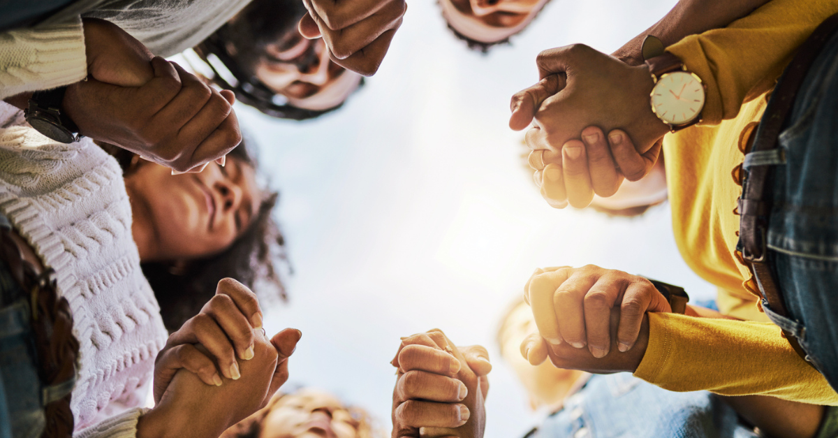 Circle of people praying together in unity.