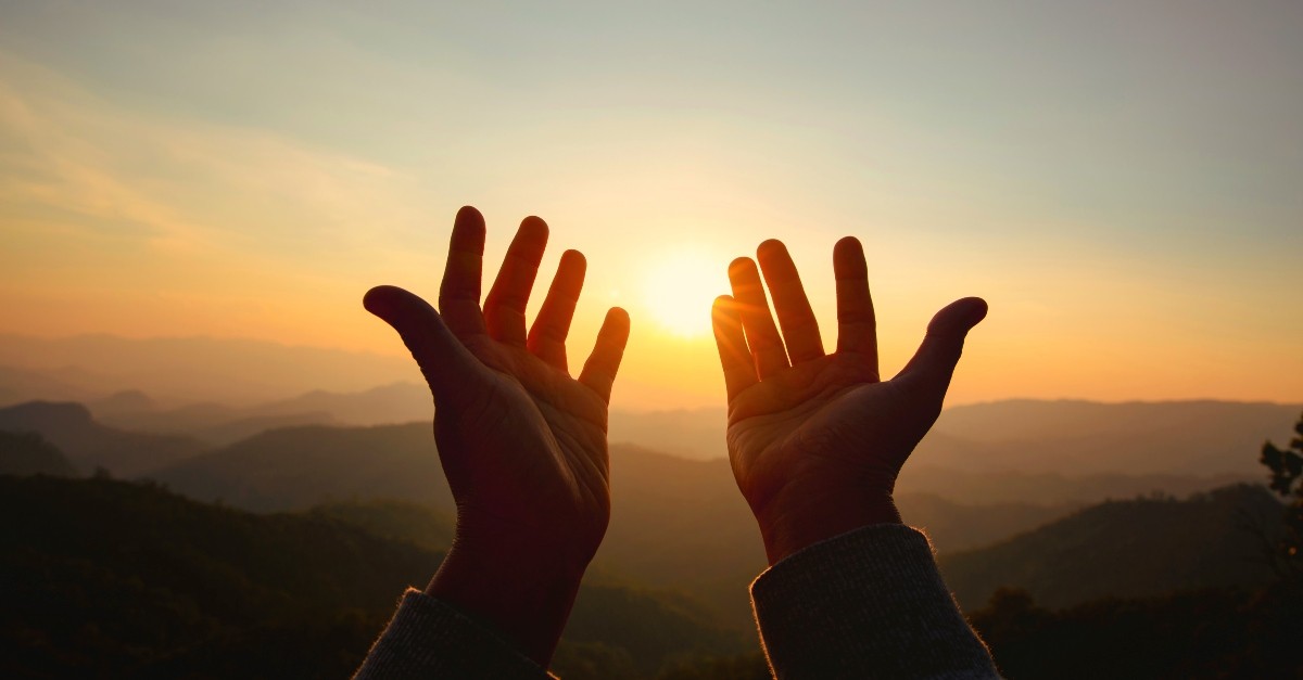 Hands raised toward the sunset