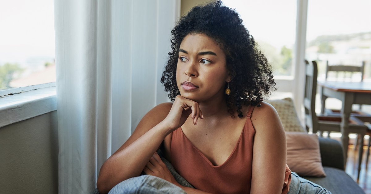 Woman looking out the window, frustrated; interrupting the cycle of negative thoughts.