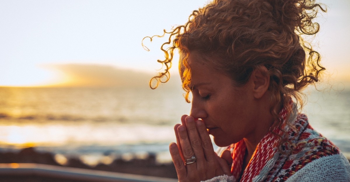 Woman praying on the shore