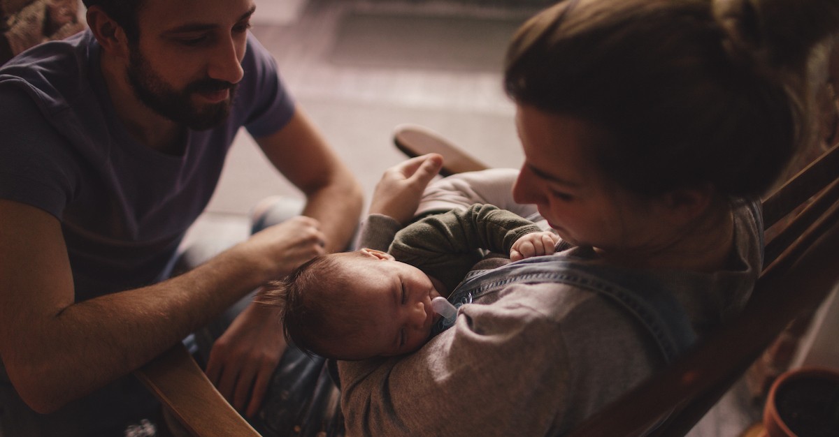 Sweet couple family caring for newborn baby in nursery