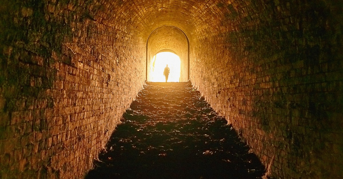 Person walking out of a dark tunnel into the light