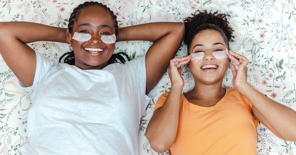 women friends on bed sleepover in eye masks self care
