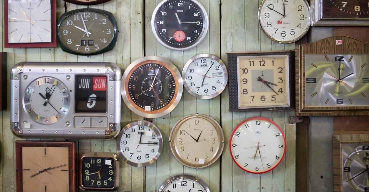 Many different styles of clocks all hung on a wall