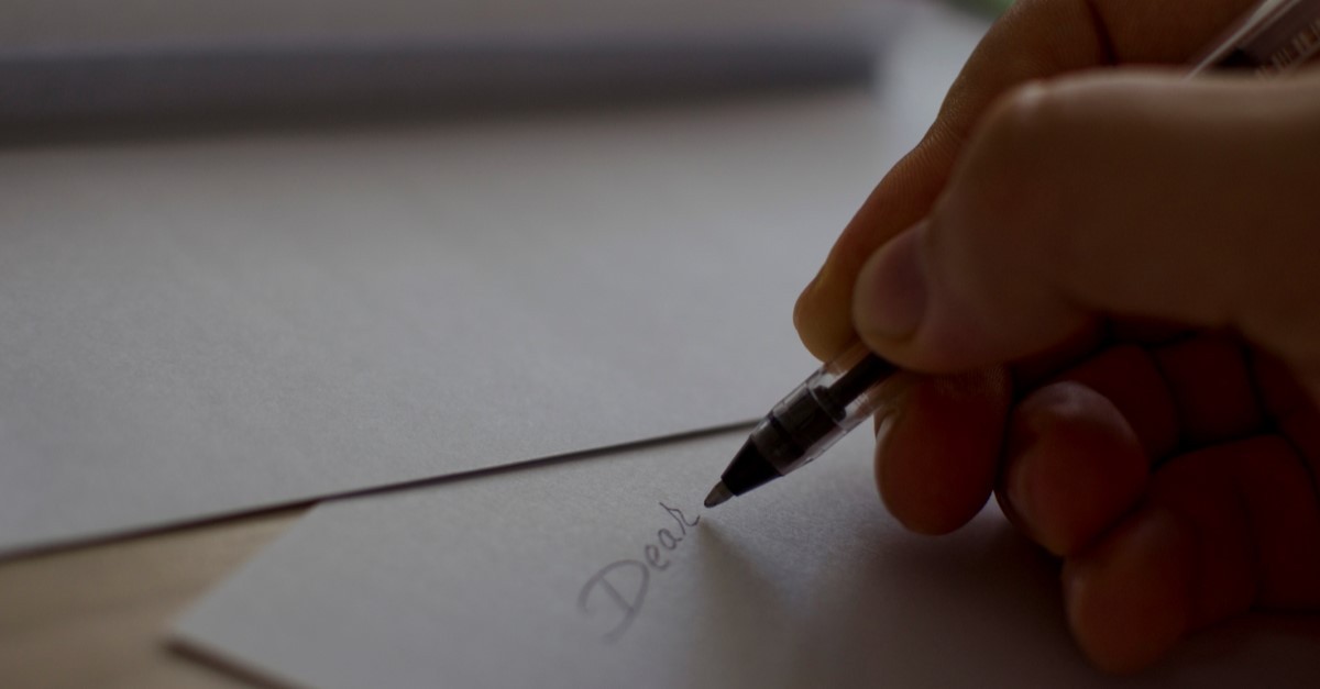 woman writing "dear" on a letter to illustrate love letter for husband