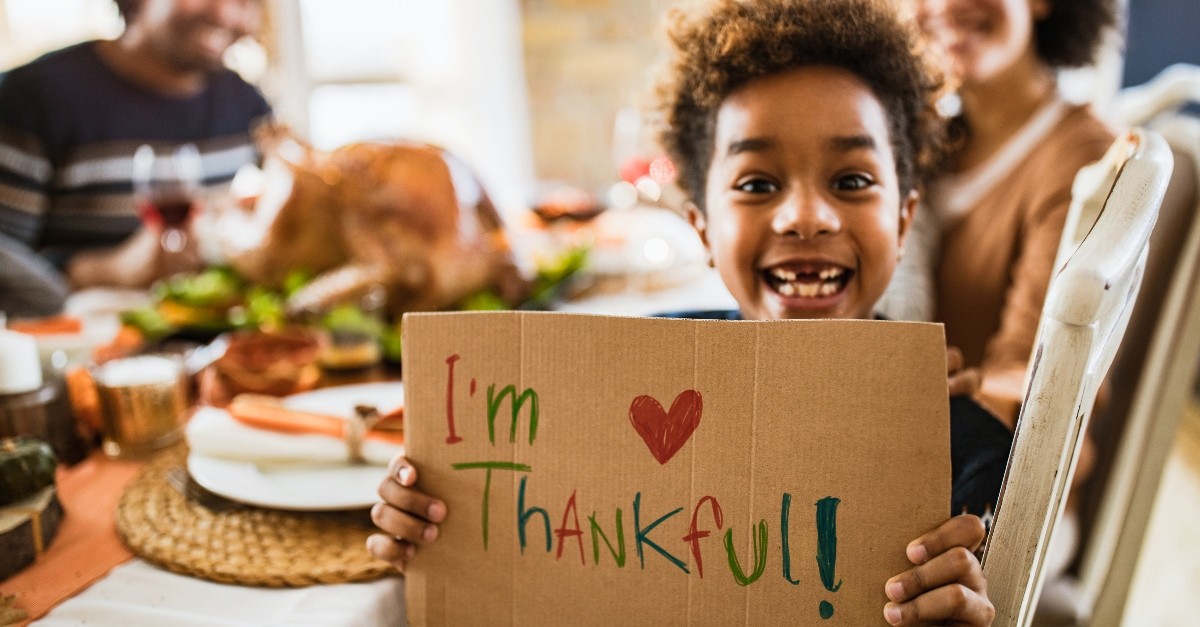 Kid holding up I am thankful sign at Thanksgiving